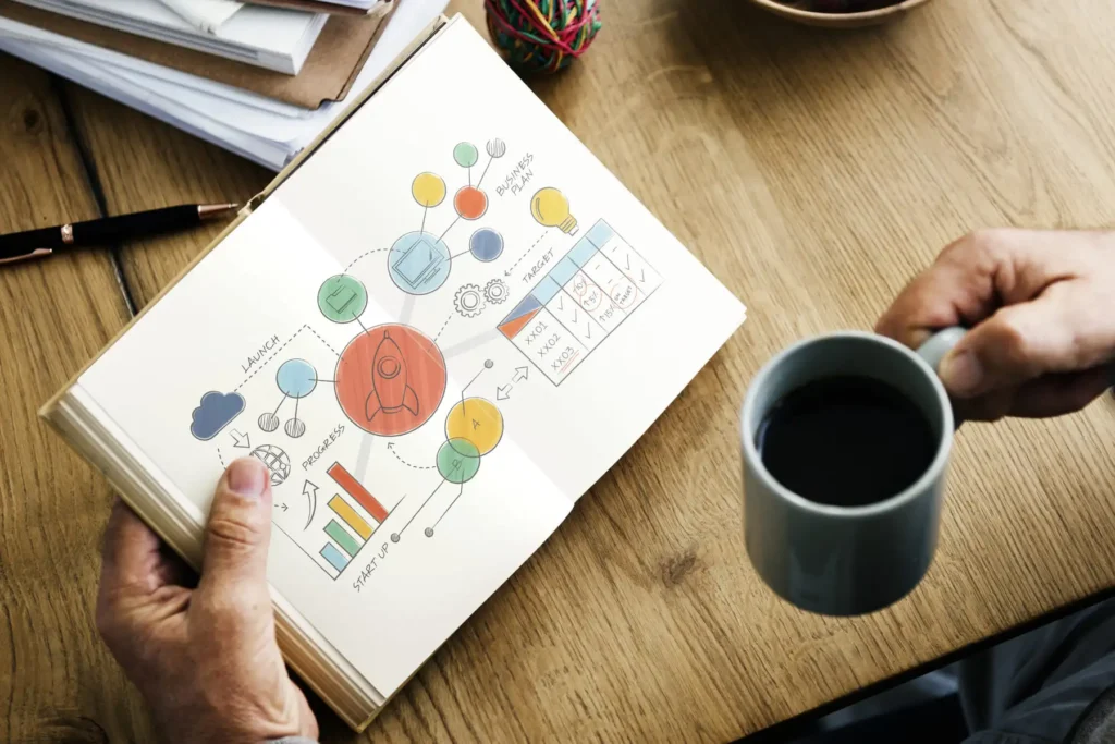 Ein Mann hält ein Buch mit Marketing Mix in der linken Hand. In der rechten Hand befindet sich eine Tasse Kaffee.